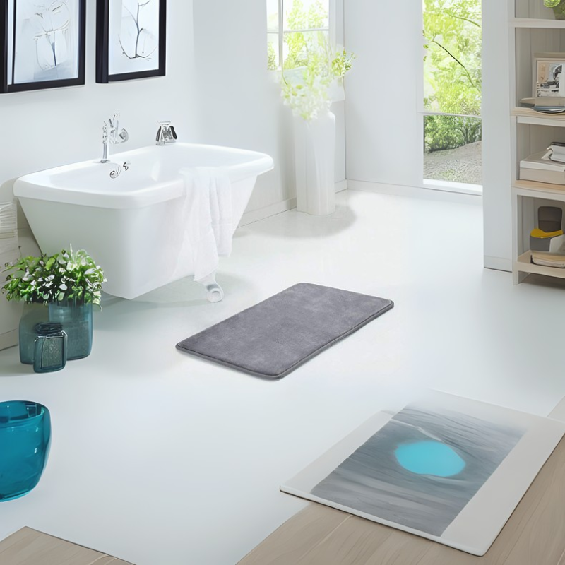 Gray rectangular bath mat placed on a white bathroom floor beside a bathtub.